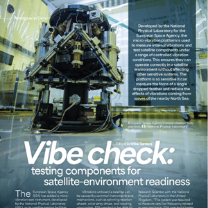 A large metal satellite component is mounted on a vibration test platform in a laboratory setting, surrounded by equipment and cables.