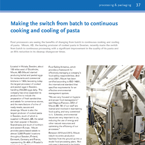 A large automated pasta processing machine in a clean industrial facility, with visible pipes, metal surfaces, and control panels.